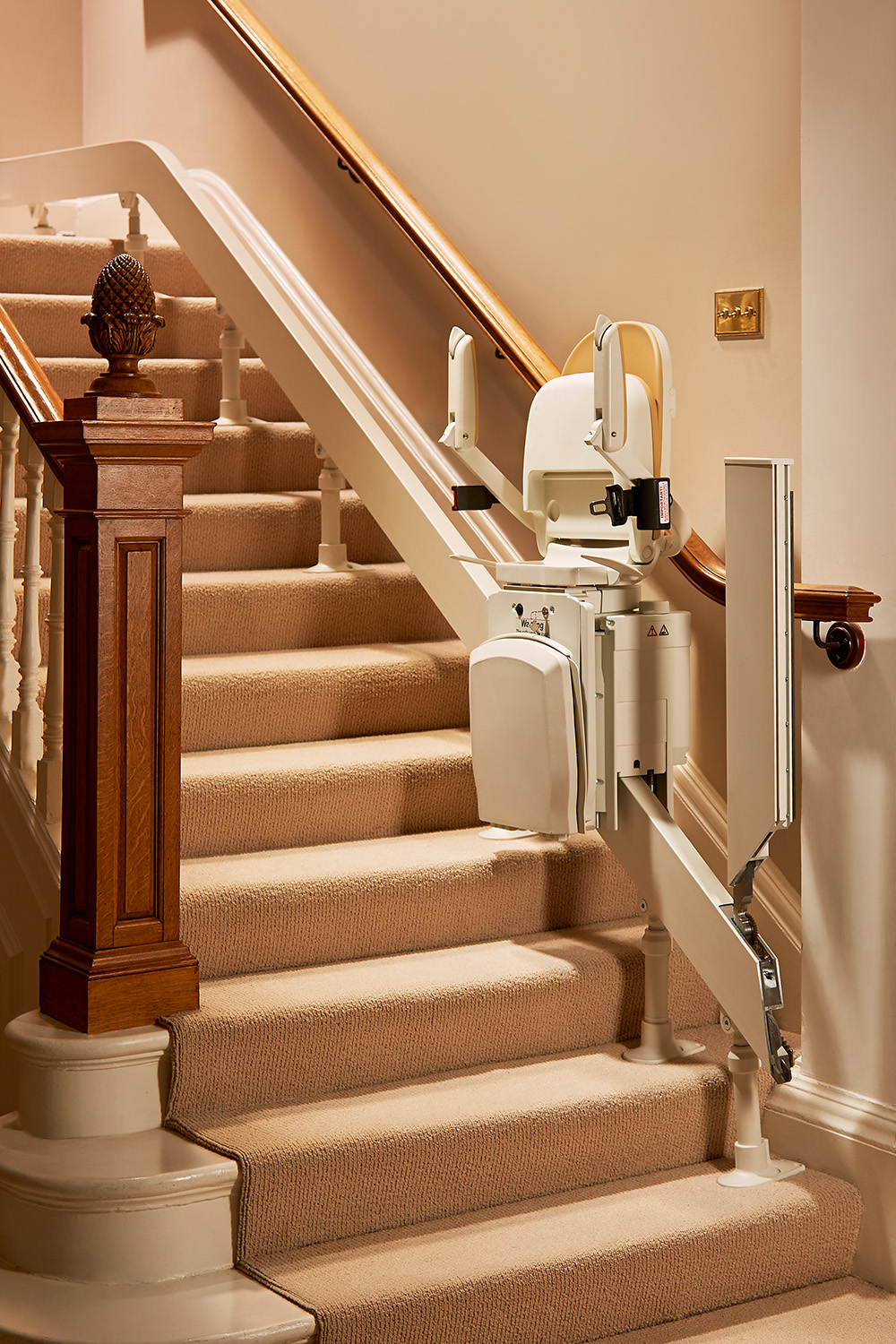 Modern straight stairlift fitted to a carpeted staircase in a bright home hallway